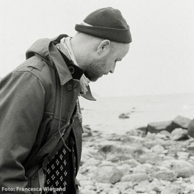 Der Autor Thomas Raatz steht am Strand vor dem Meer.